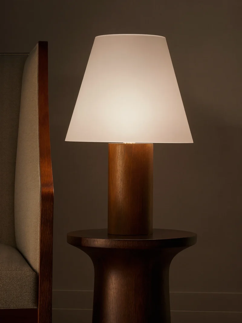 Illustration: Tischlampe mit Opalglasschirm neben einem Lesesessel